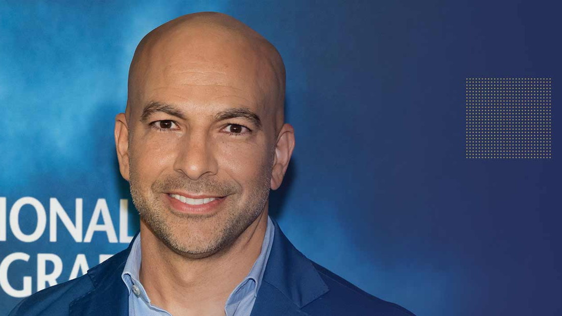 Portret muškarca nasmejanog ispred plave pozadine, simbolizuje stručnost, samopouzdanje i moderan pristup zdravlju i dugovečnosti.